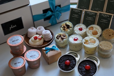 Phivi subscription boxes stacked with a variety of desserts in front, including cookies, meringue and others.