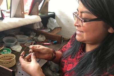 An Ecuadorian artist working with a needle and beads in her work area. International Blessings partnered with her.