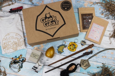A closed Geek Gear subscription box with Harry Potter related items like wands, a snowy owl, house patches and a t shirt.