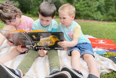 Three boys reading space book part of the CuriousCaptain club: Field Trip to the Moon by  John Hare.