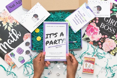 A girls hands hold a book titled It's A Party! next to a subscription box with encouraging cards and a magic deck of cards.