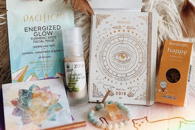 Items from a Goddess Provisions subscription box including loose leaf tea, a facial mask, a journal and more.