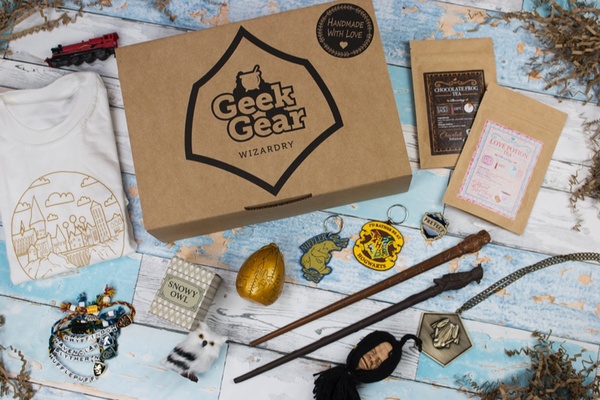 A closed Geek Gear subscription box with Harry Potter related items like wands, a snowy owl, house patches and a t shirt.