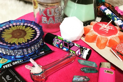 Items from The Stoney Babe subscription box including a water pipe, a lighter, an empty jar, and various candles.