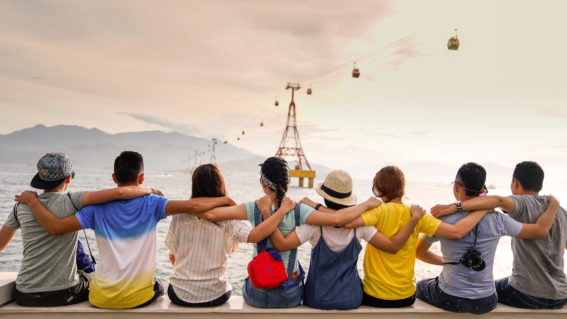 friends embracing each other while sitting near a sea stock image