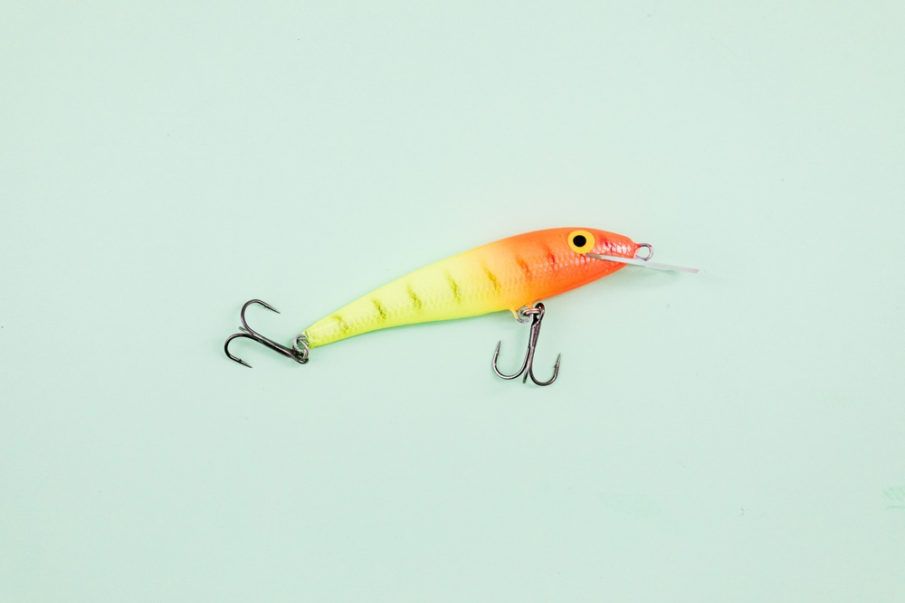 A pastell green background and a bright colored fishing hook.