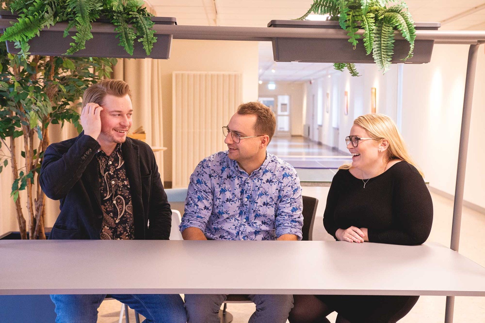 Entreprenörerna Erik Hermansson, Glenn Winbo Sondell och Ann Winbo sitter tillsammans vid ett bord och pratar och skrattar.