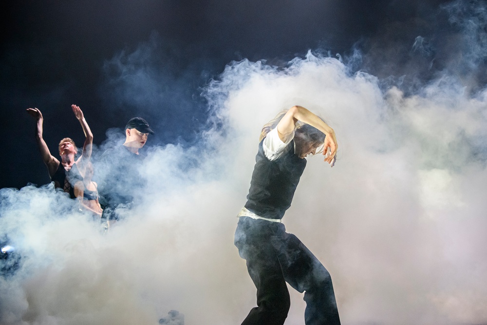 Tre dansare på en rökfylld scen