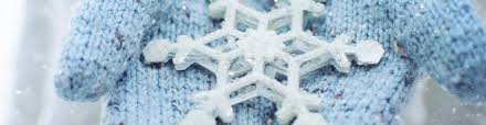 A large, white snowflake rests on a soft, blue knitted fabric.