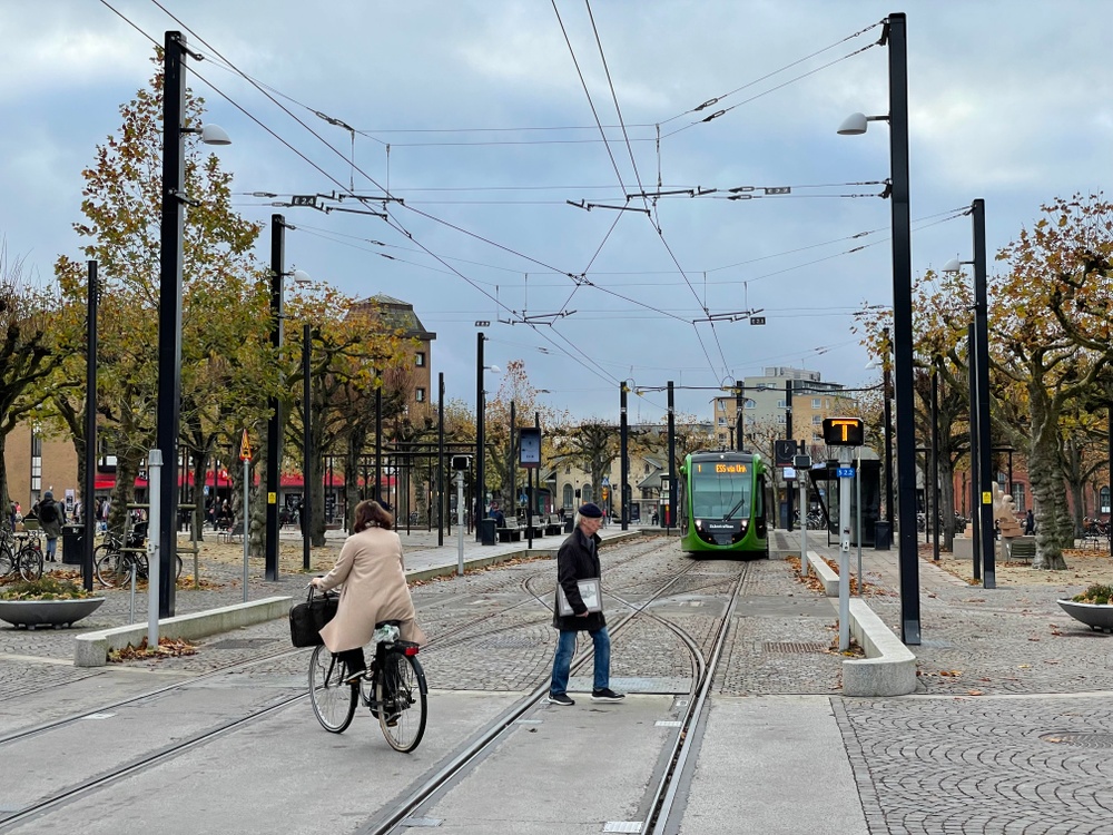 Cyklist och fotgängare passerar spårvägen i Lund vid Clemenstorget.