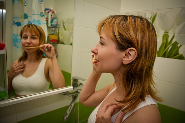 A 30yo Woman brushing her teeth in front of the mirror