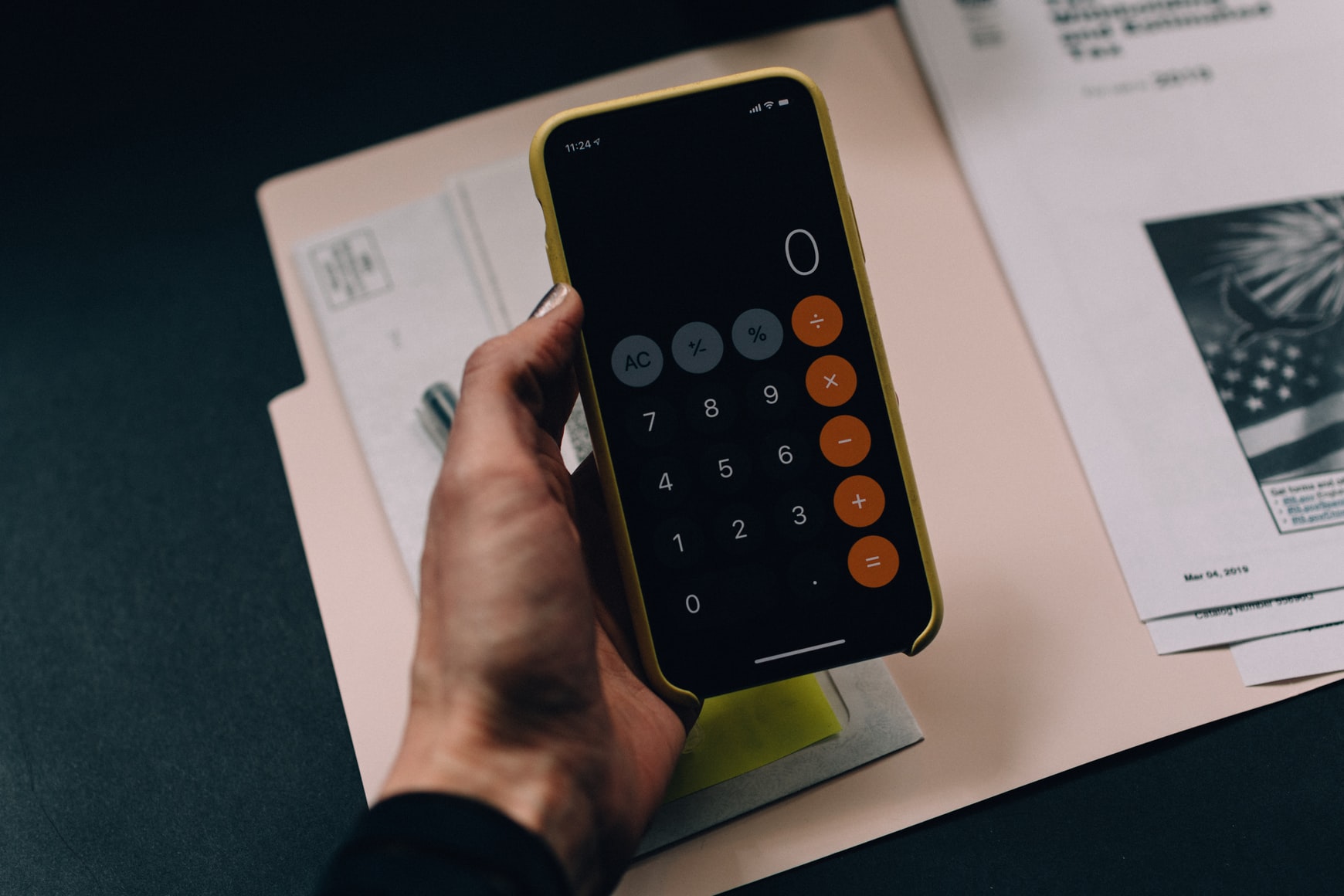 Holding a phone calculator with folder in background