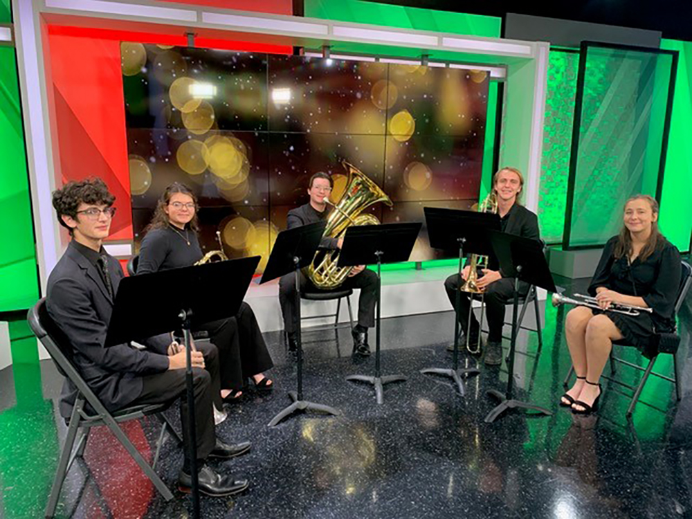 5 people wearing black and holding musical instruments sit in chairs