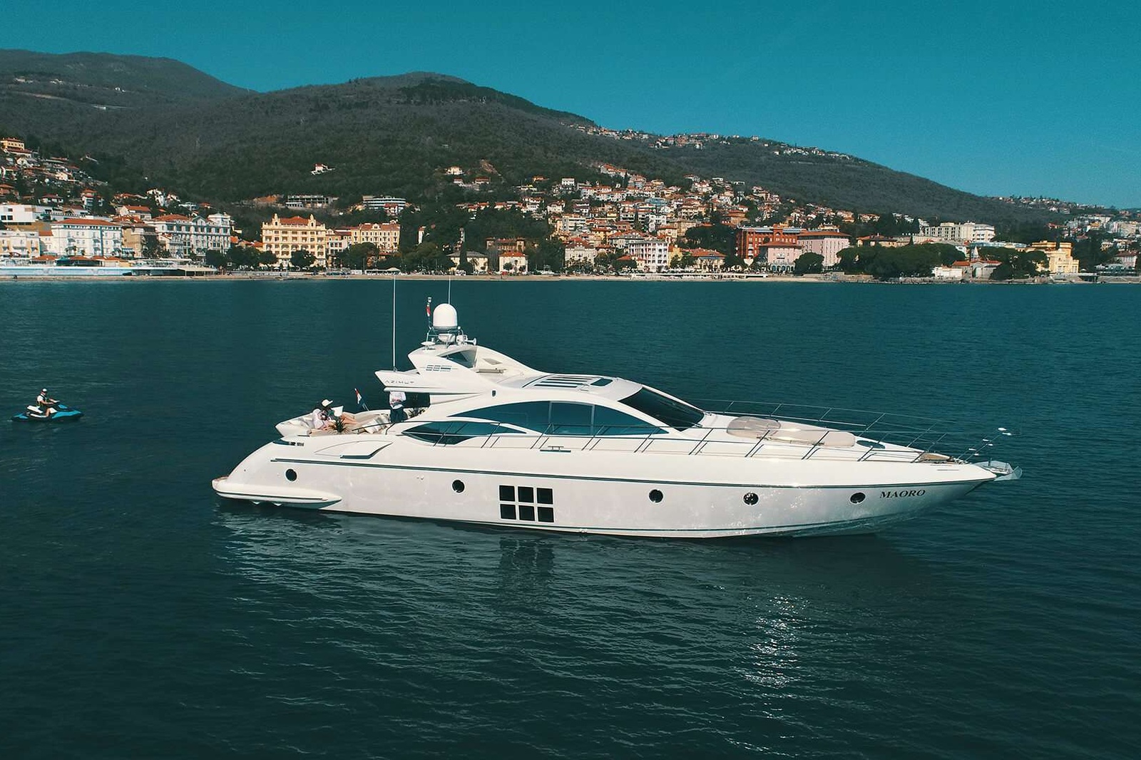 M/Y MAORO  is sleek and compact, Azimut 68S. Her unique open design allows guests to soak up the sun while relaxing on board. M/Y Maoro is a truly remarkable and unique yacht, with flowing lines and a beam of 5 meters. She is a balanced mix of comfort, driving pleasure, and luxury quite surprising in the world of sport yachts. Aside from the stunning good looks of this vessel, the accommodations and performance cues are outstanding.
The unique feature of the design of this yacht is the spacious saloon that opens out directly on to an attractive stern deck. When combined with a large section of the saloon roof that can be retracted at the touch of a button to reveal 20 sq meters of the sky, this yacht becomes an open sports cruiser.
Voluminous and clean-lined, its Grand Saloon is bound to be loved by young ones for its new Smart TV and Bose sound touch system, and by the big ones – for allowing them the time to enjoy the yacht’s cosy outdoors.
Below deck can accommodate up to six guests in 3 en suite cabins. The complete full-beam master suite, will make you feel like you are in a floating luxury hotel while you soak in the striking views of the sea. Whether you choose to sunbathe on the bow, soak in the views over a cocktail on the stern or hop into the turquoise Adriatic off the spacious bathing platform, rest assured your kids will be safe and enjoying themselves.
Accentuate your days with exciting water activities, whether it’s the jet skiing, stand-up paddleboarding or snorkeling, before coming together for some solar yoga on the pristine sunbathing area or platform.
The crew is accommodated in the separate crew area on the stern of the yacht.