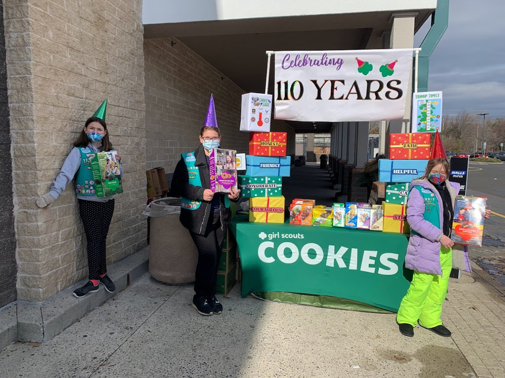 Hailey S., Kreps Middle School, Julia L. Kreps Middle School, and Bella L., Grace N. Rogers Elementary School, decorate their 2022 Cookie Booth to celebrate the 110th Girl Scout Anniversary Celebration.