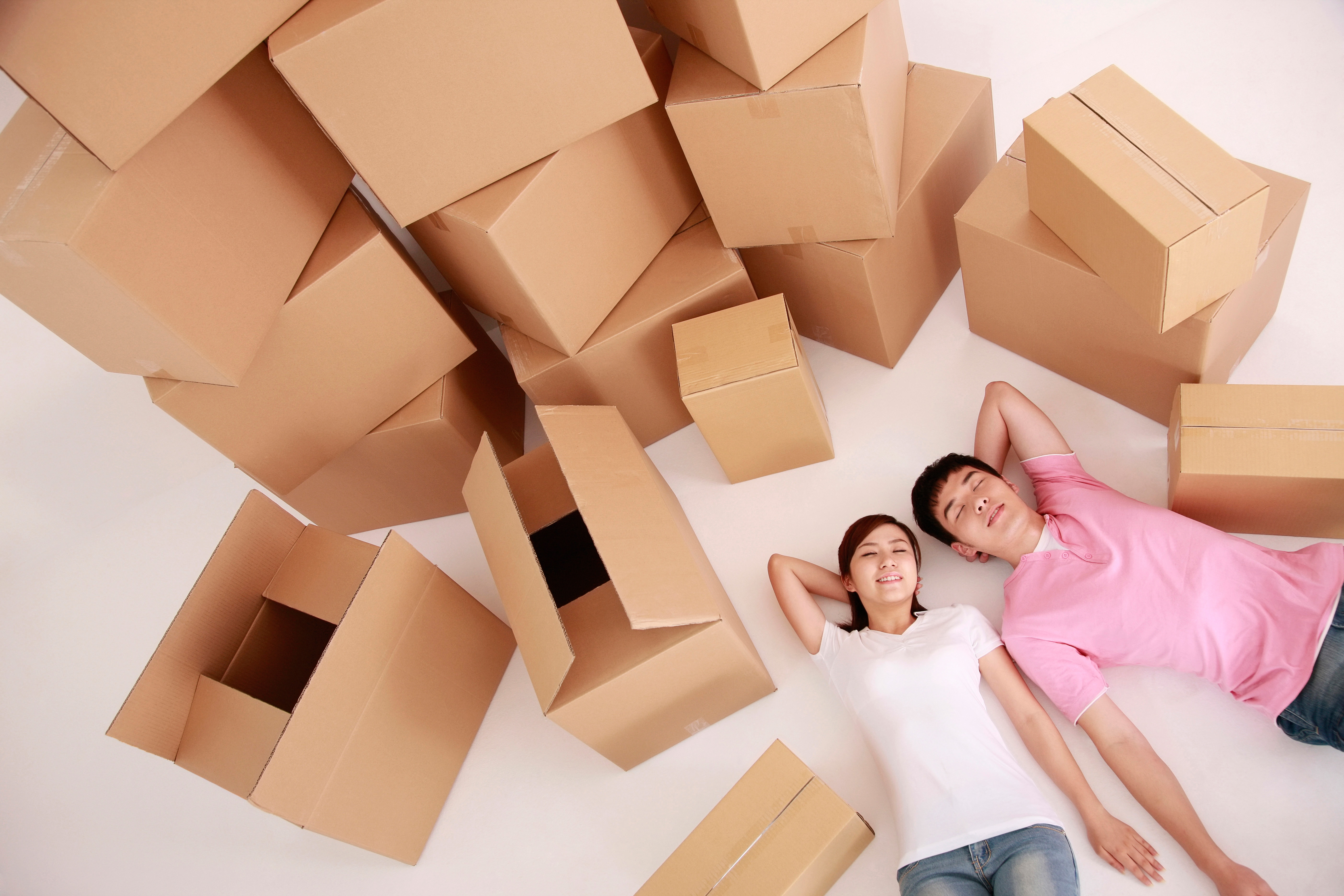 A couple lying on the floor with stacks of empty boxes.