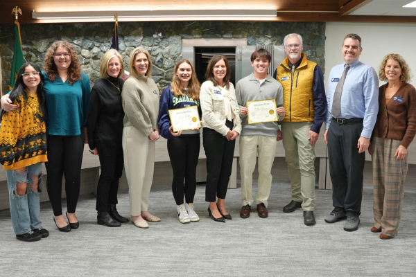 A group of people stand together, holding certificates and smiling for a photo.