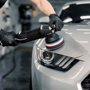 A Paint-correction being done to the bonnet of a white car, using cutting compound and a Dual-action polisher