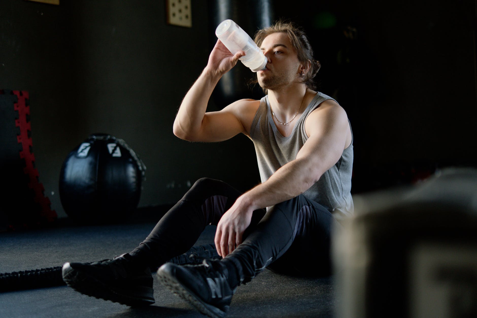 a man drinking water while resting in a gym