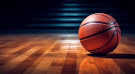 orange basketball on hardwood gym floor with darkened bleachers background