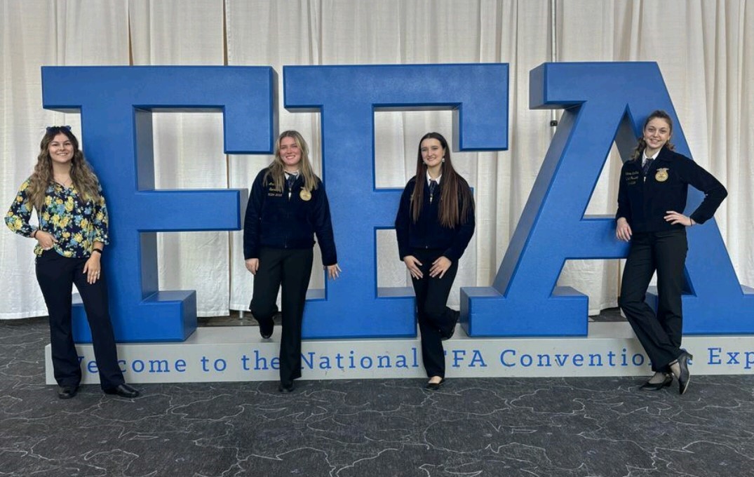 Marion students and their advisor pose in front of FFA letters at the National Convention in Indianapolis.