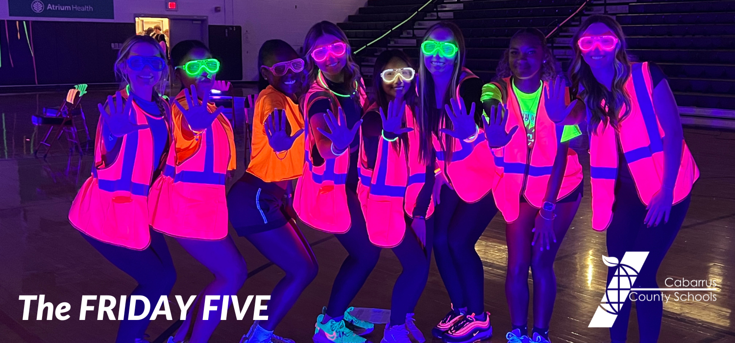 Pep rally photo of students holding up five fingers.