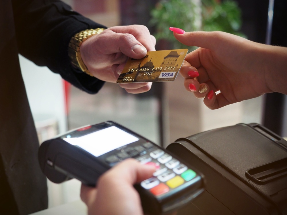 Two hands, one paying with a credit card and one holding the card reader. 