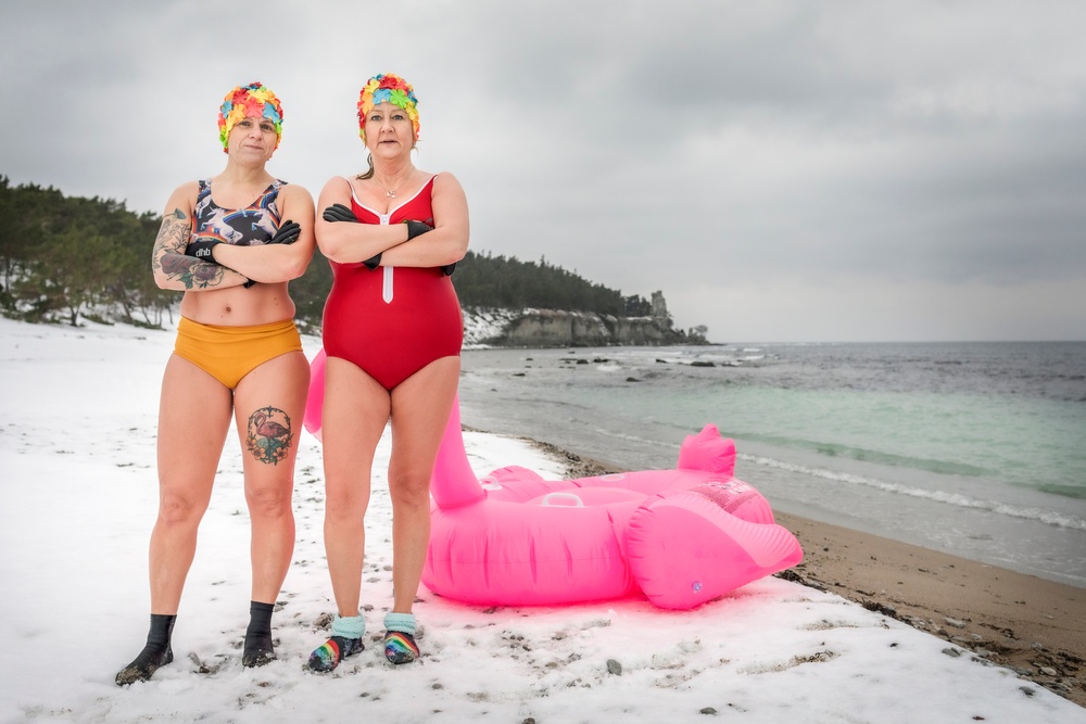 Två kvinnor vinterbadar på Gotland i färgglada badkläder och badleksak. 