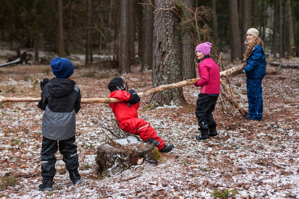 Fyra barn leker med lång trädgren