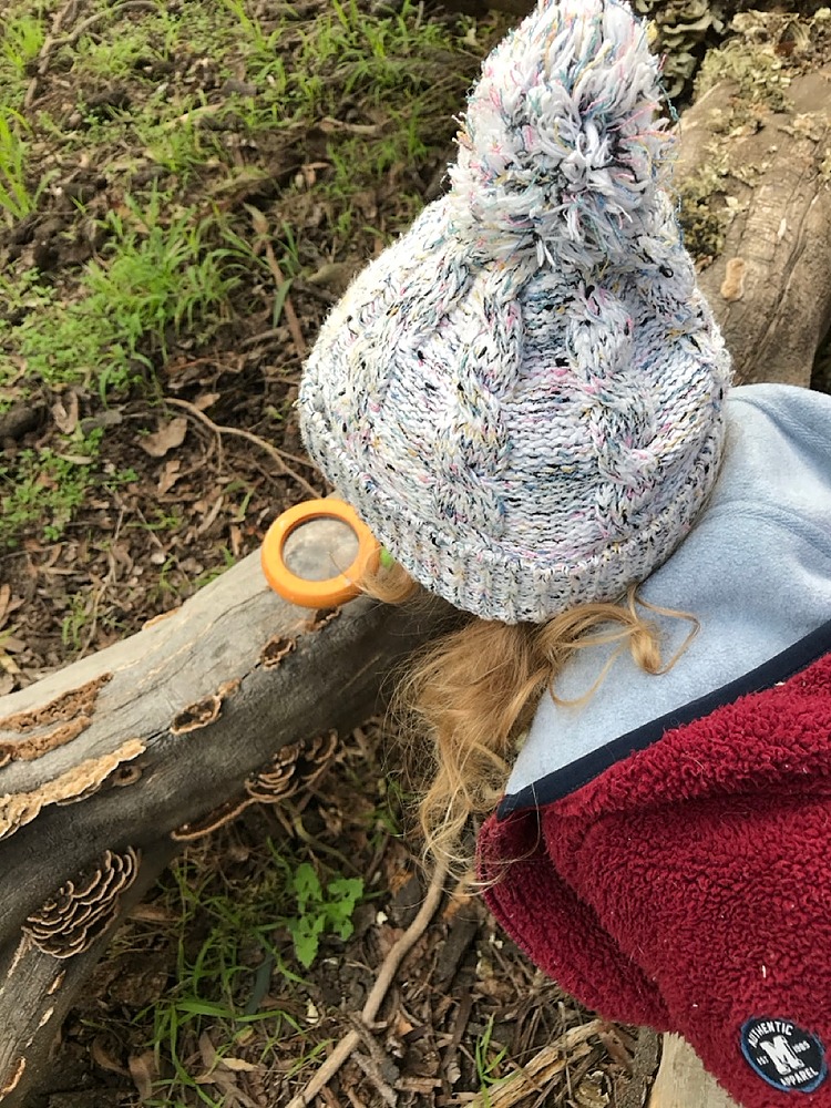 Child looking through magnifying glass at mushrooms