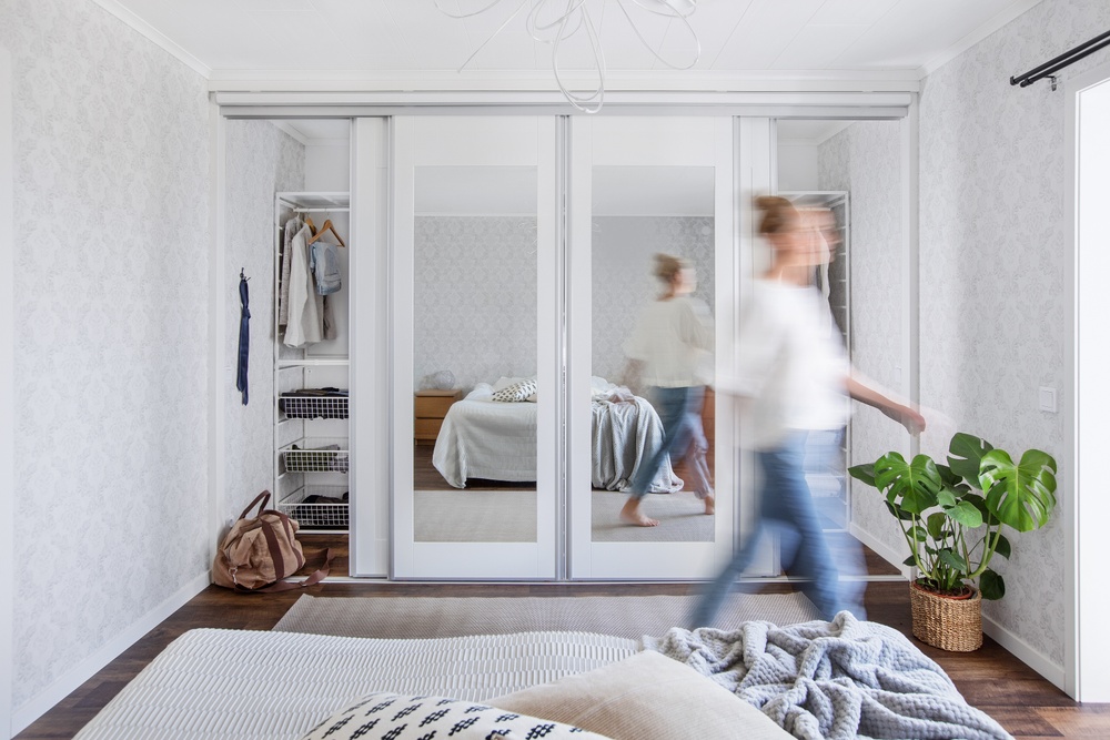 Vita Mix skjutdörrar med speglar och vit garderobsinredning i ett sovrum. 