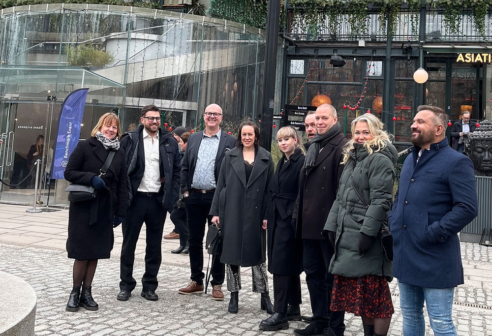 Nio personer står framför ingången till AktivBos benchmarkevent på Berns i Stockholm. De ser glada och förväntansfulla ut.