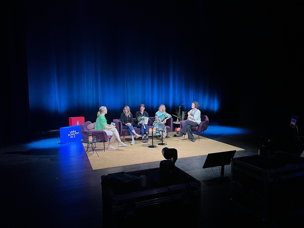 Fem kvinnor sitter på en scen.