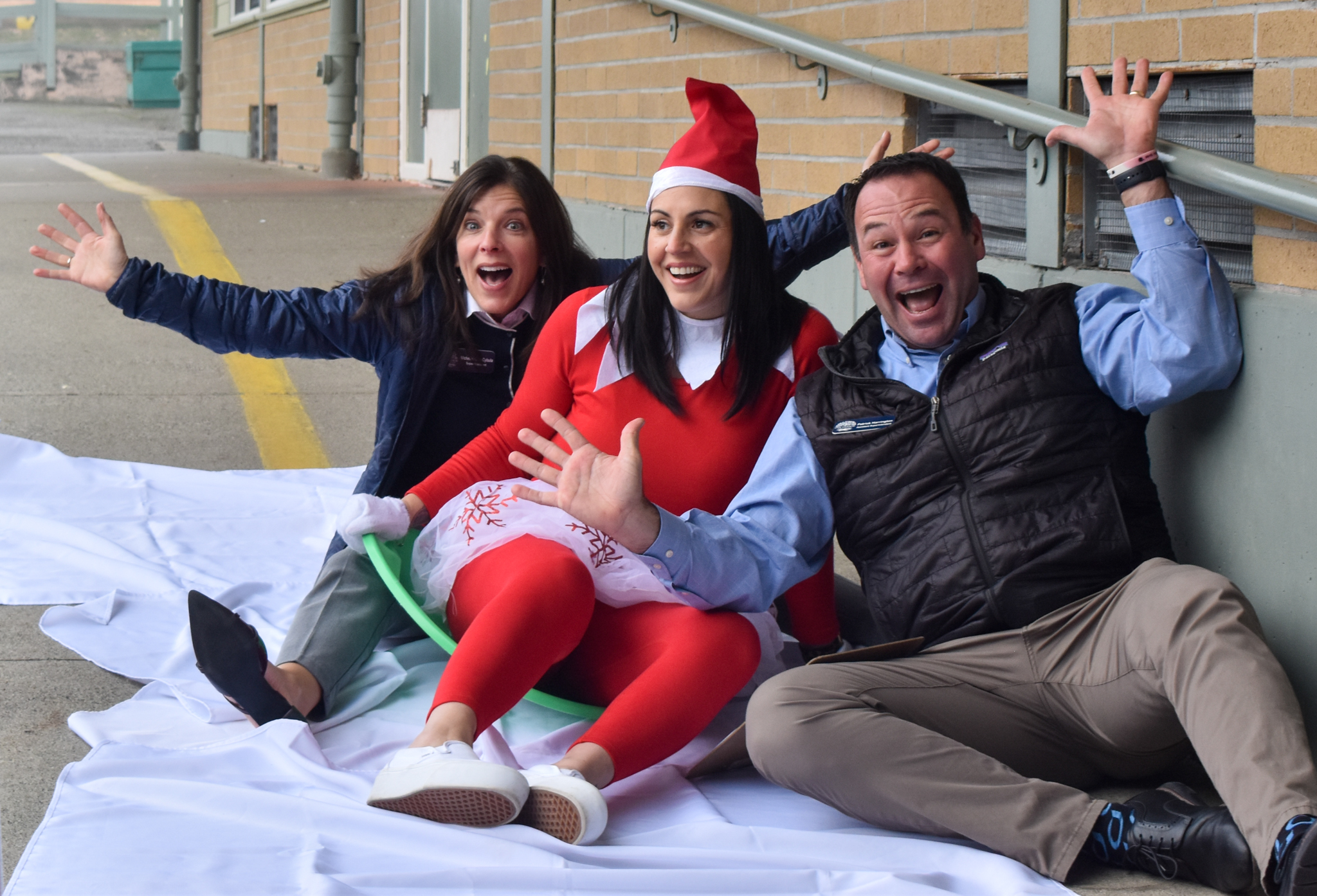 Three people dressed in festive attire pose for a photo, laughing and having fun.