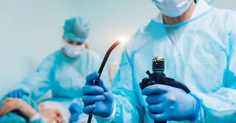 Doctors prepare a hospital patient for endoscopy while one holds an endoscope medical device.