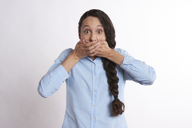 A woman looking surprised with both hands on her mouth