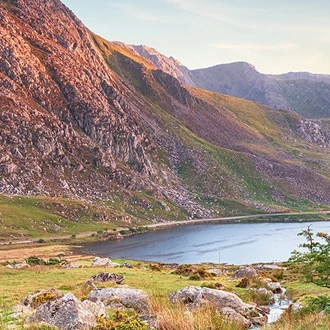 A landscape view of the famous Snowdonia national park in Wales, it's natural fauna and cliff faces shining in the evening glow.