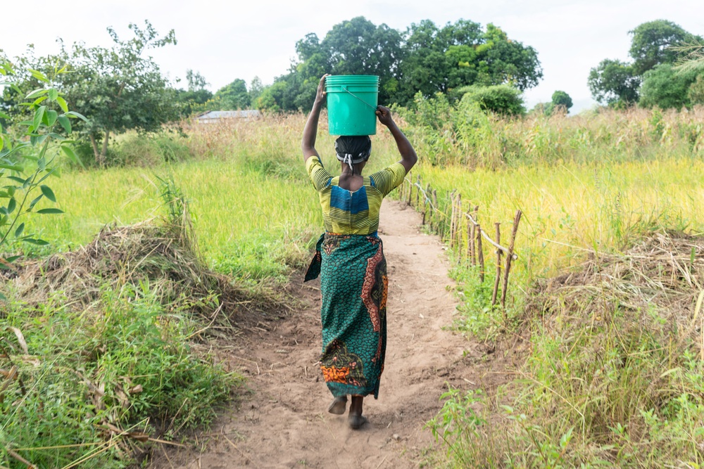En kvinna promenerar för att hämta vatten från en brunn i närheten. Malawi, april 2022. Bild: WaterAid/ Francis Chipanda