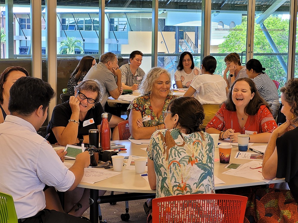 Participants sit around a table laughing.