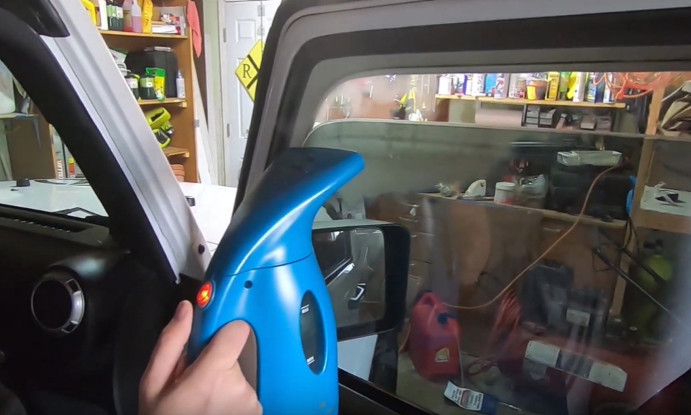 A Person using a Steamer to remove old window tint on door window