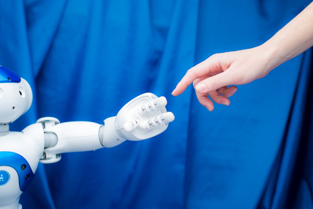En robot och en människa sträcker ut händerna mot varandra. 