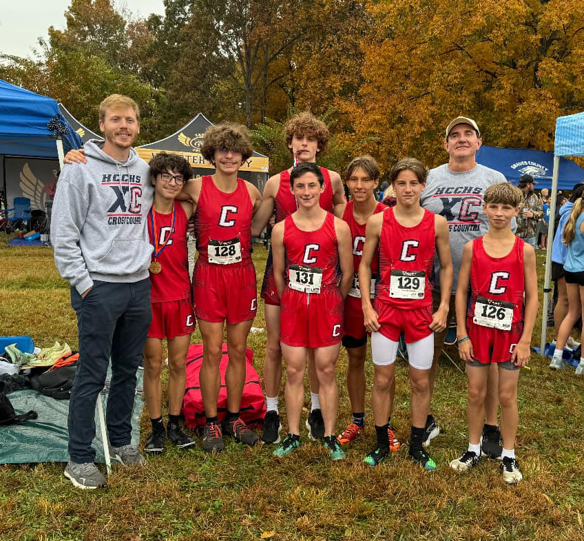 7 team members in red uniforms with a "c" on the front and 2 others pose for a photo,.