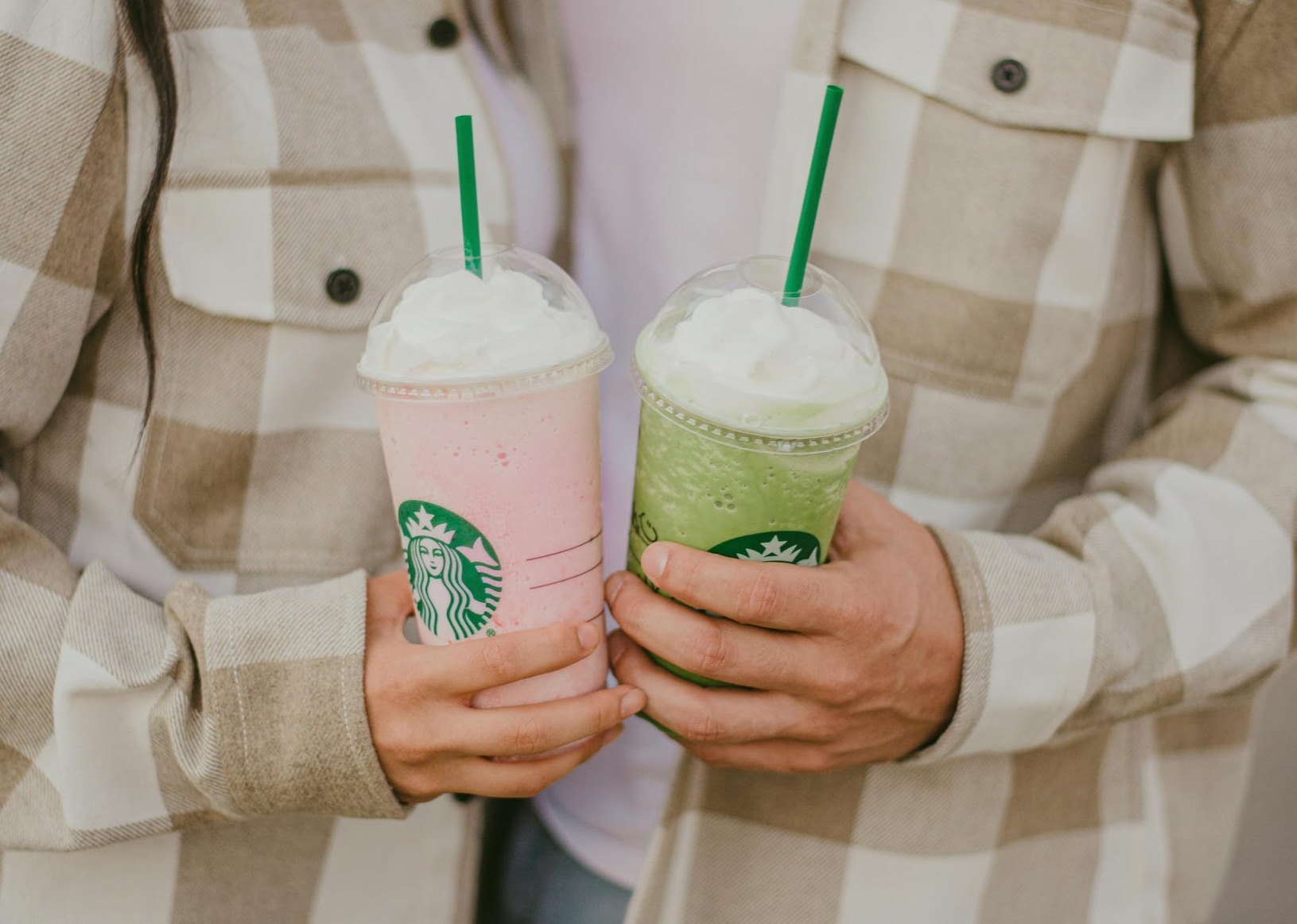 men and woman holding starbucks drinks in hands