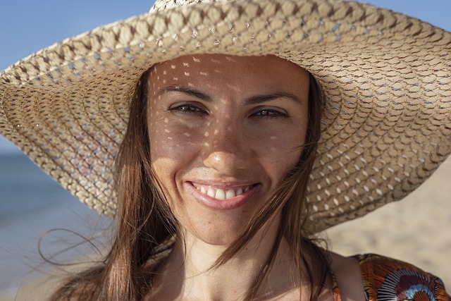 A smiling woman on the beach with a hat