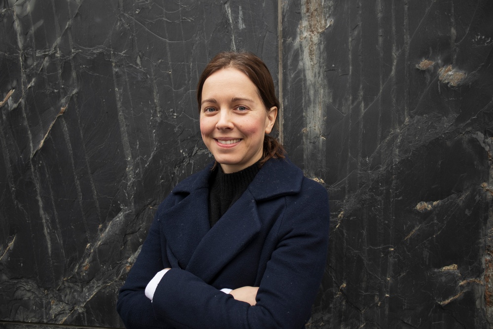 Bild på en leende Hanna Söderman i förgrunden av svartmelerad vägg. 