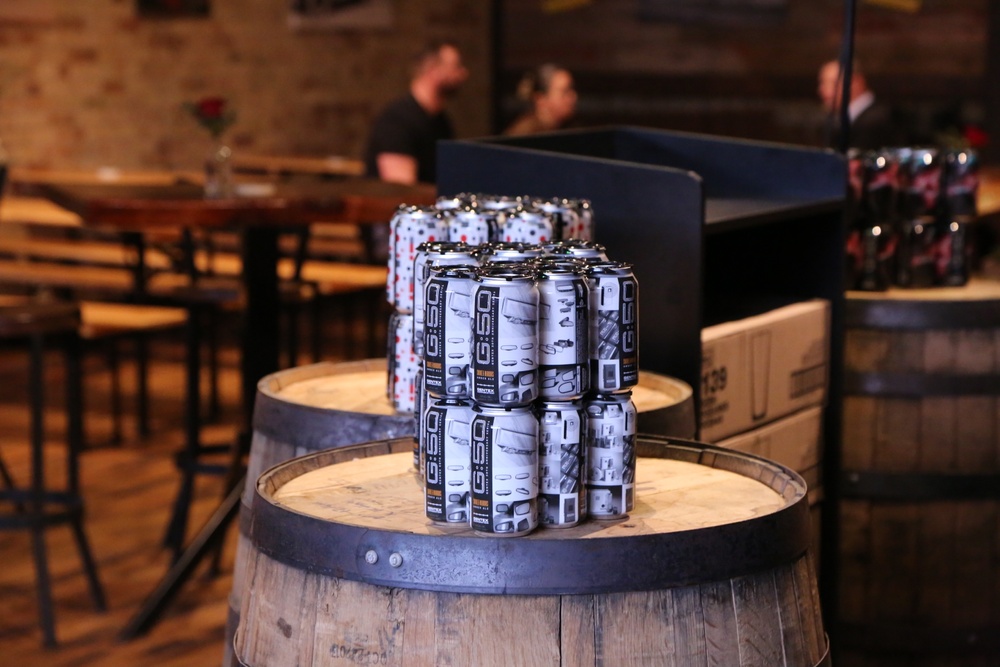 Cans of Gentex Smoke and Mirrors beer at Tripelroot Brewery, sitting on a wooden barrel. 