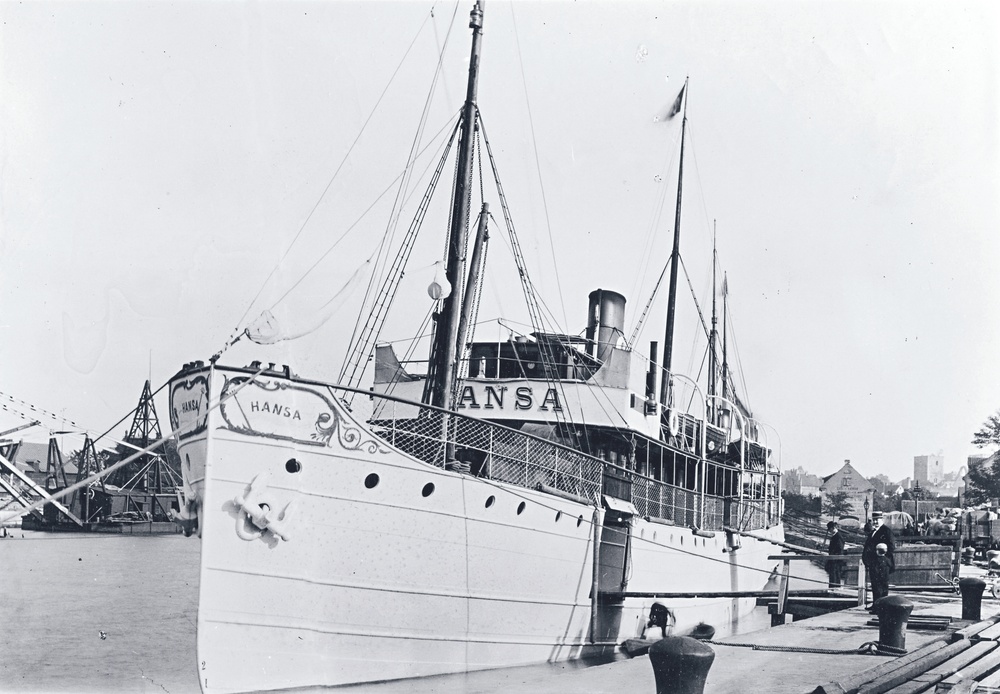 En svartvit bild på ett fartyg i början av 1900-talet. Den ligger vid kaj. 