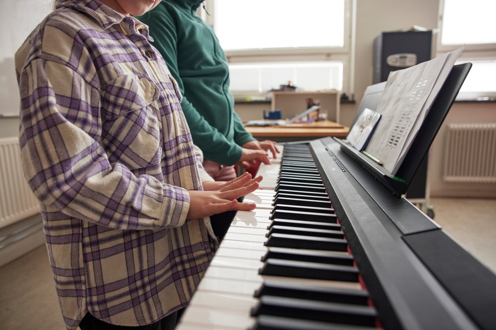 Två elever spelar på ett piano i skolan