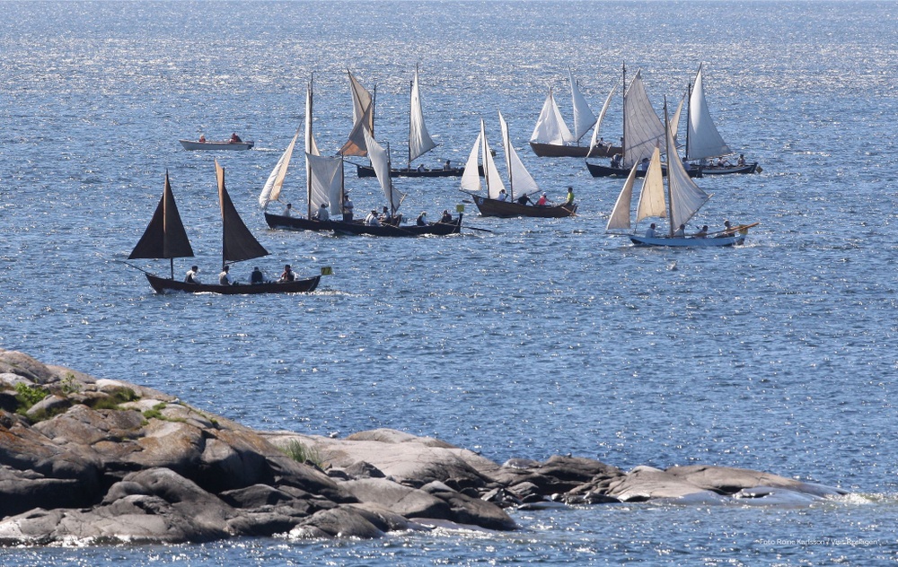 Gamla segelbåtar  med vita och svarta segel, av samma modell som de som användes för hundratals år sedan, på blått hav.