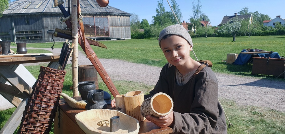 En av medlemmarna i vikingasällskapet Svíar i sitt läger framför Gamla Uppsala museum.